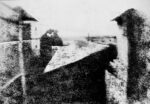 A barely discernible b/w image of some courtyard walls