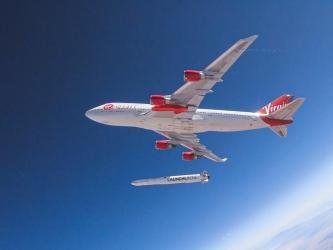 A red and white painted Virgin jumbo jet high in the blue atmosphere... drops a rocket from under its wing!