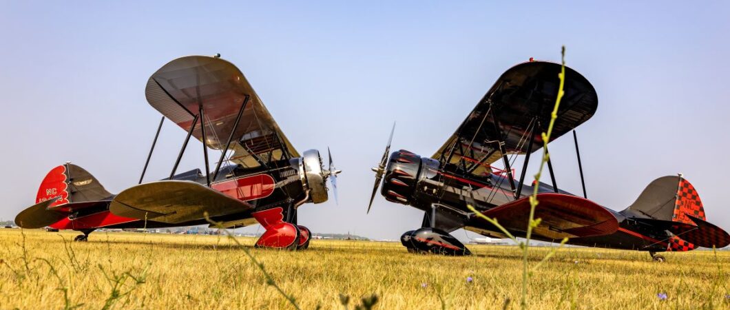 Two 1930s Waco biplanes parked on the grass facing each other