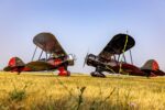 Two 1930s Waco biplanes parked on the grass facing each other