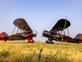 Two 1930s Waco biplanes parked on the grass facing each other