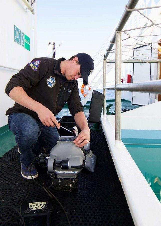 Man working with a screwdriver on a small remote underwater vehicle 