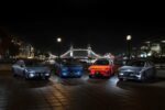 A set of fours electric cars are displayed at night in London with Tower bridge in the background