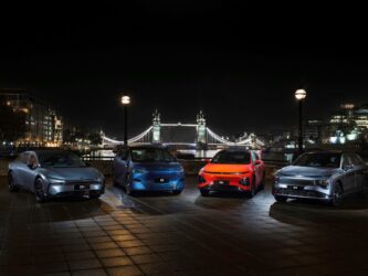 A set of fours electric cars are displayed at night in London with Tower bridge in the background