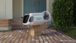 A small white spaceship-looking delivery droid drops a package by the front door
