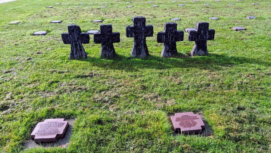 Two grave markers in front of a row of five small crosses