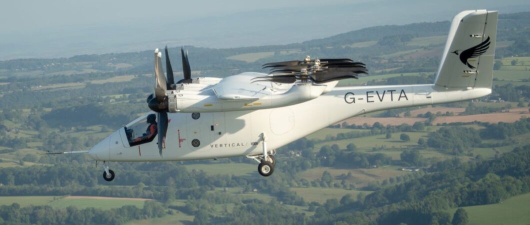 A white multi-rotor eVTOL aircraft flying over the countryside