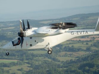 A white multi-rotor eVTOL aircraft flying over the countryside