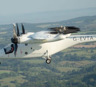 A white multi-rotor eVTOL aircraft flying over the countryside