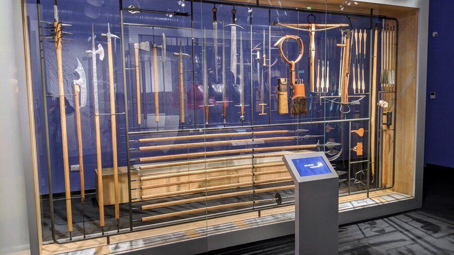 a glass case full of weapons, mostly polearms & swords